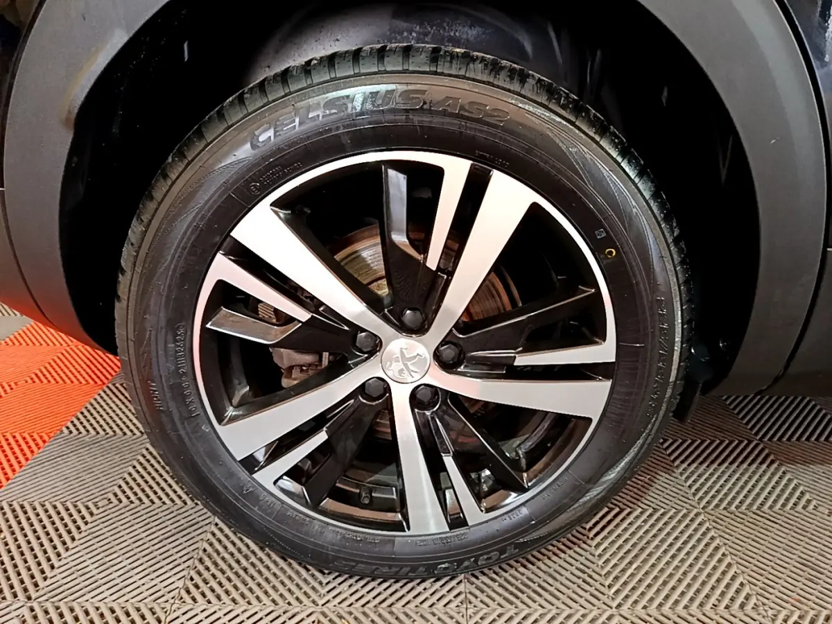 Gros plan sur la jante alliage bicolore et pneu Toyo du côté gauche d'un Peugeot 3008 noir 2023.