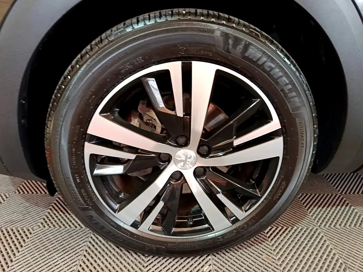 Gros plan sur la jante alliage bicolore du côté gauche d’un Peugeot 3008 noir 2023, pneu Michelin visible.