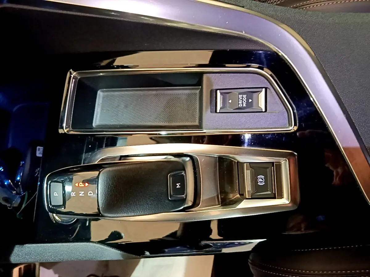 Vue rapprochée de la console centrale noire du Peugeot 3008 GT 2023 avec levier de vitesse et bouton Drive Mode.