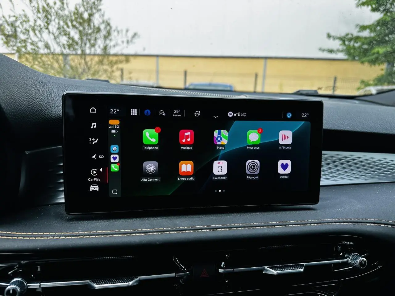 Écran tactile central de l'Alfa Romeo Tonale 2024 affichant Apple CarPlay, avec tableau de bord noir et surpiqûres beige.