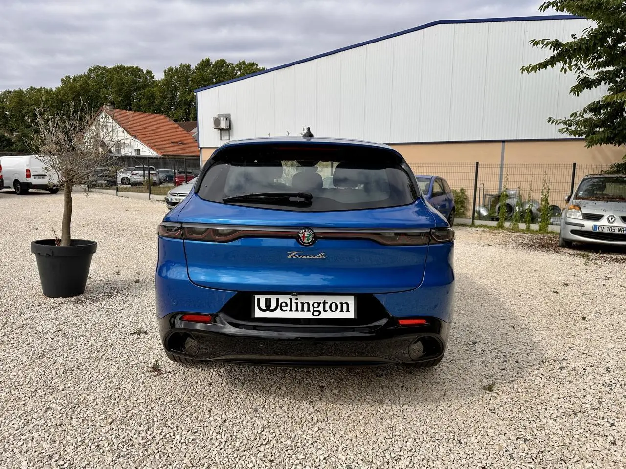 Vue arrière d'une Alfa Romeo Tonale 1.5 mHEV Sprint bleu métallisé, avec feux arrière full LED et double sortie d'échappement noire.