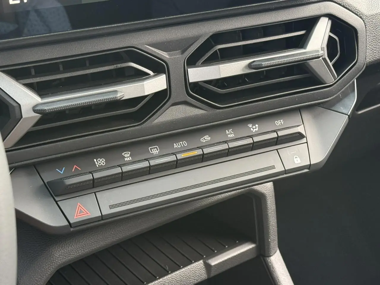 Détail du tableau de bord noir du Dacia Duster 2026 avec commandes climatisation et aérateurs hexagonaux.