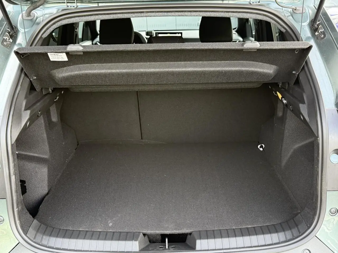 Coffre ouvert vu de l'arrière du Dacia Duster Vert Cèdre 2026, espace de chargement vide et tablette de séparation relevée.