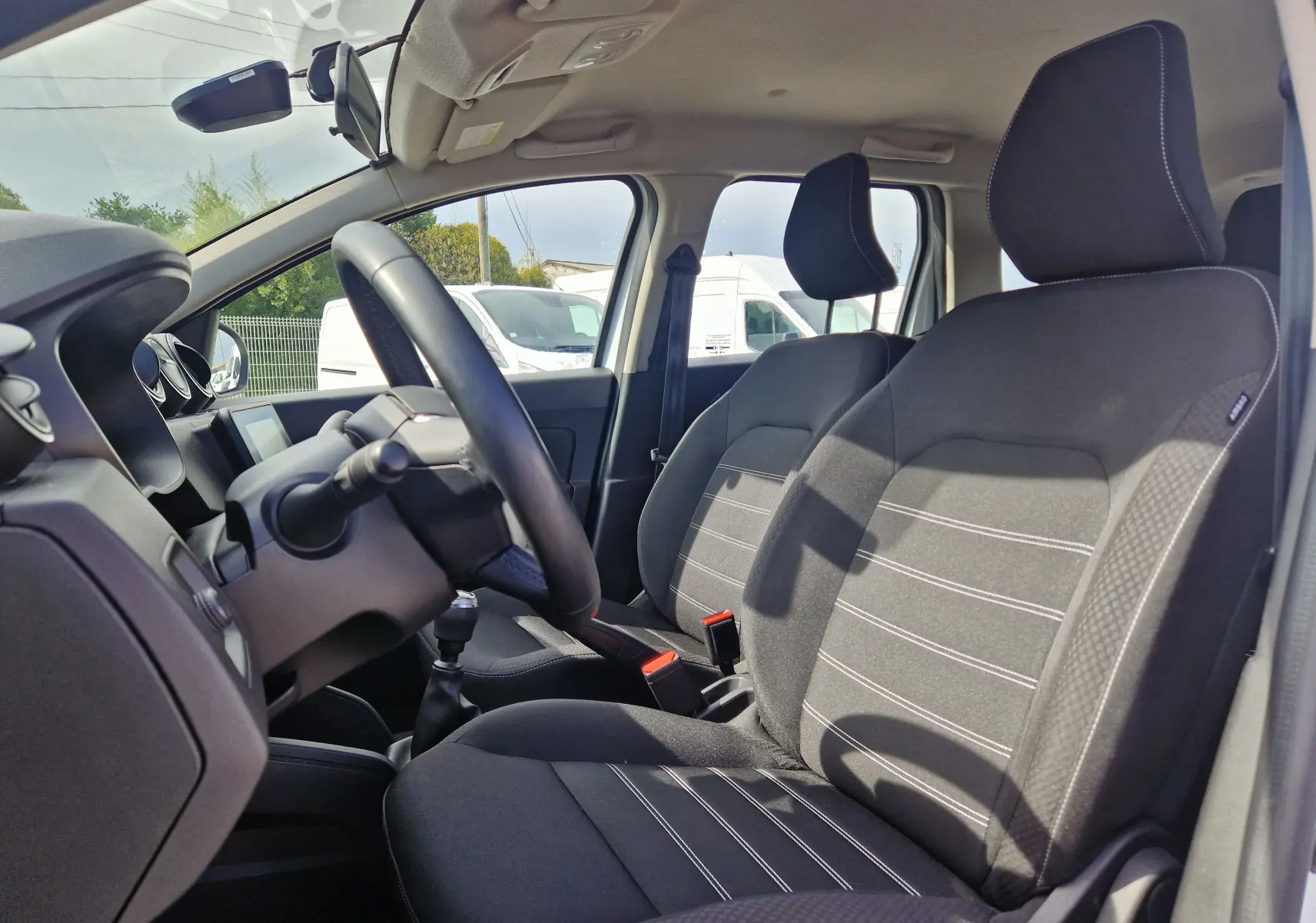 Vue intérieure côté conducteur du Dacia Duster 4x4 2022, sièges noirs avec surpiqûres blanches et volant visible.