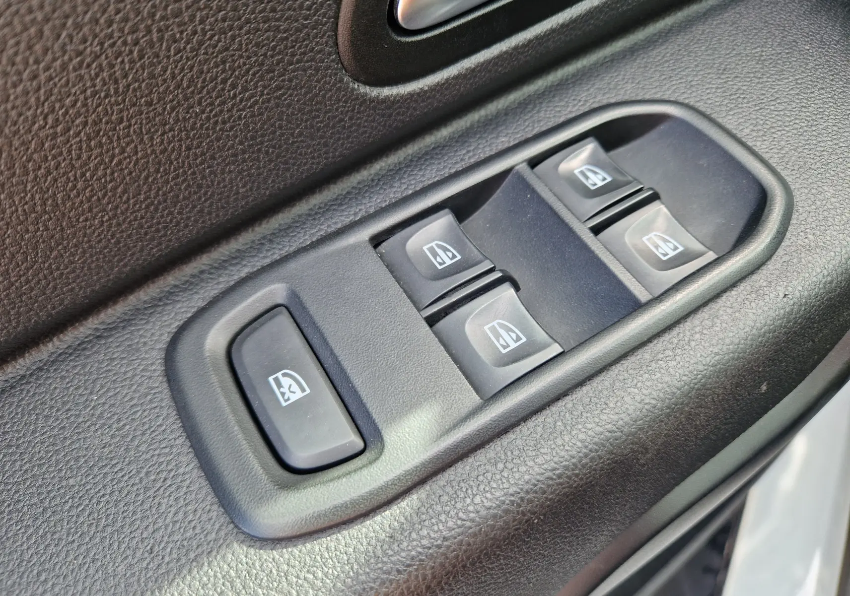 Gros plan sur les commandes des vitres électriques côté conducteur du Dacia Duster blanc 4x4 2022.
