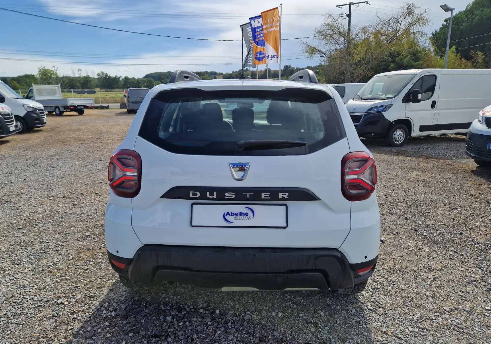 Vue arrière d’un Dacia Duster blanc 2022 avec feux arrière caractéristiques et logo DUSTER bien visible.