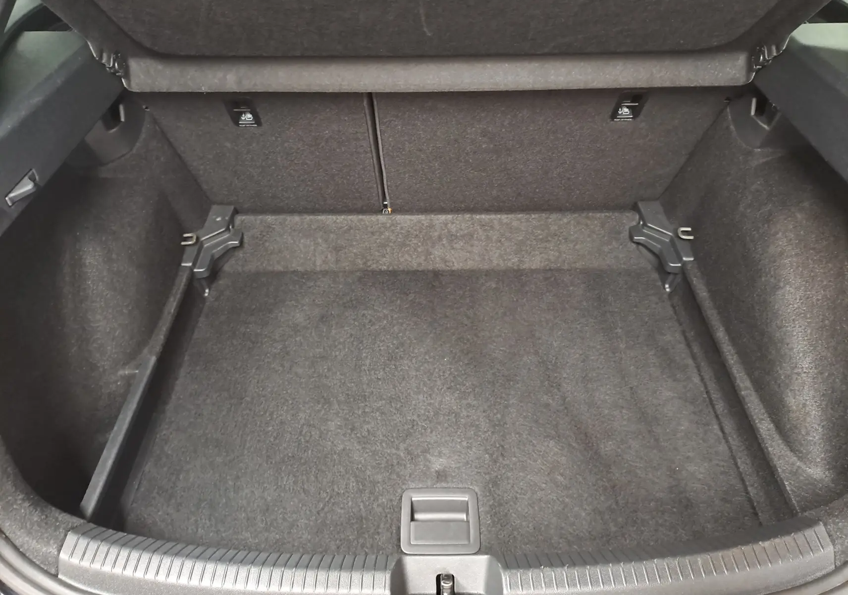 Coffre ouvert vu de face, intérieur spacieux et tapissé de noir du Volkswagen Taigo 2025 noir intense.