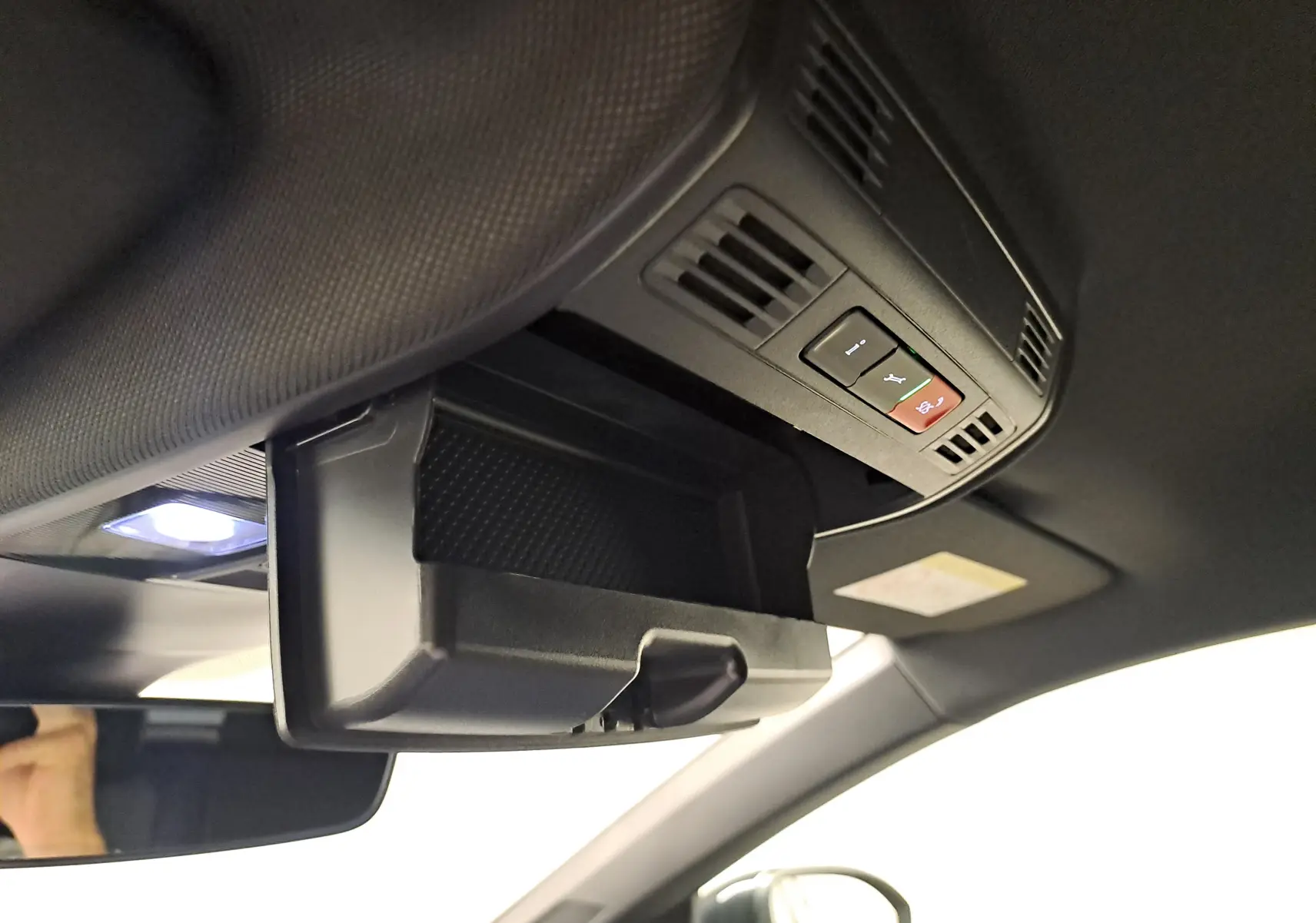 Vue intérieure du coffre à lunettes ouvert au plafond d'un Volkswagen Taigo noir intense, avec commandes intégrées visibles.