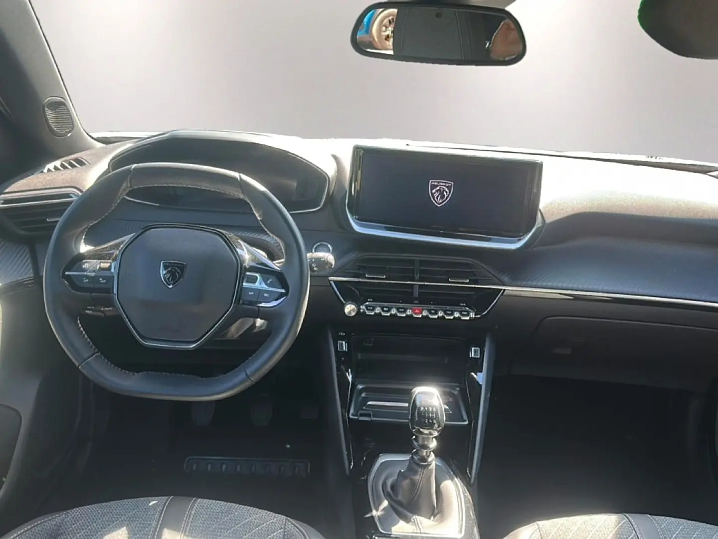 Vue intérieure avant du Peugeot 2008 1.2 100 allure 2025, volant multifonction et levier de vitesse manuel visibles.