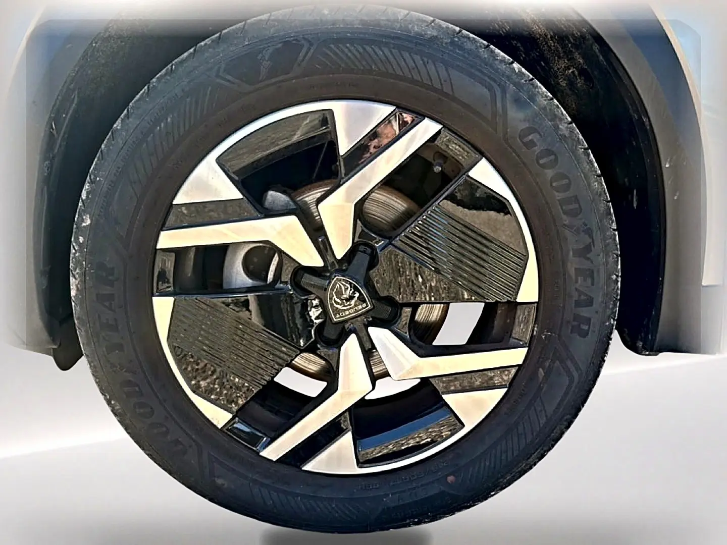 Gros plan sur la jante alu bicolore du côté gauche d’un Peugeot 2008 gris Artense, avec pneu Goodyear visible.