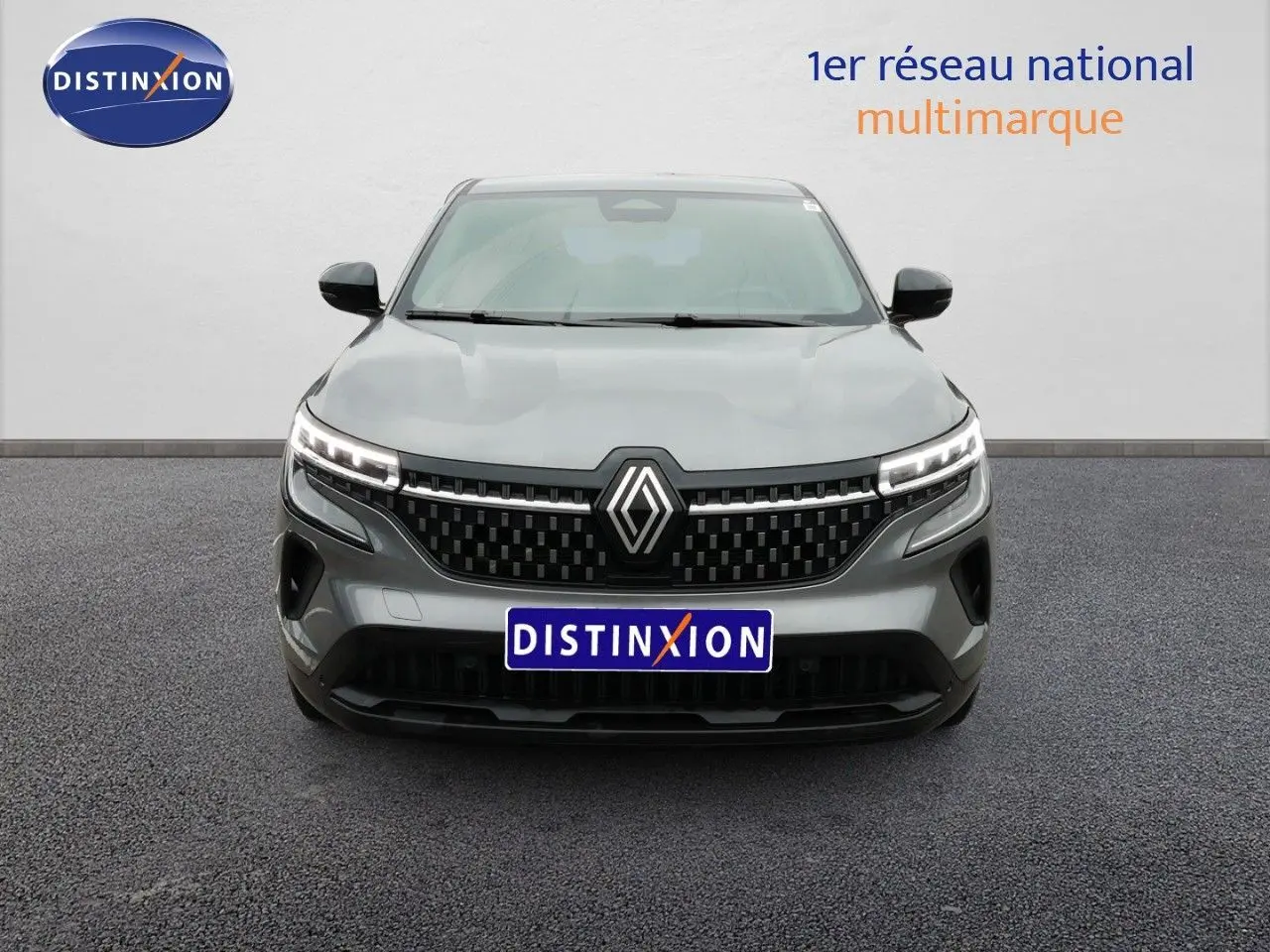 Vue de face du Renault Austral gris schiste métal avec calandre noire et feux LED allumés sur fond neutre.