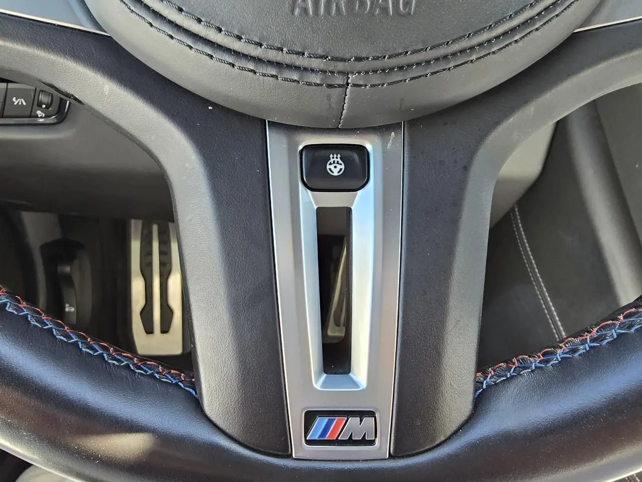 Gros plan sur le volant cuir noir avec surpiqûres tricolores et logo M de la BMW Série 8 Cabriolet M8 Competition.