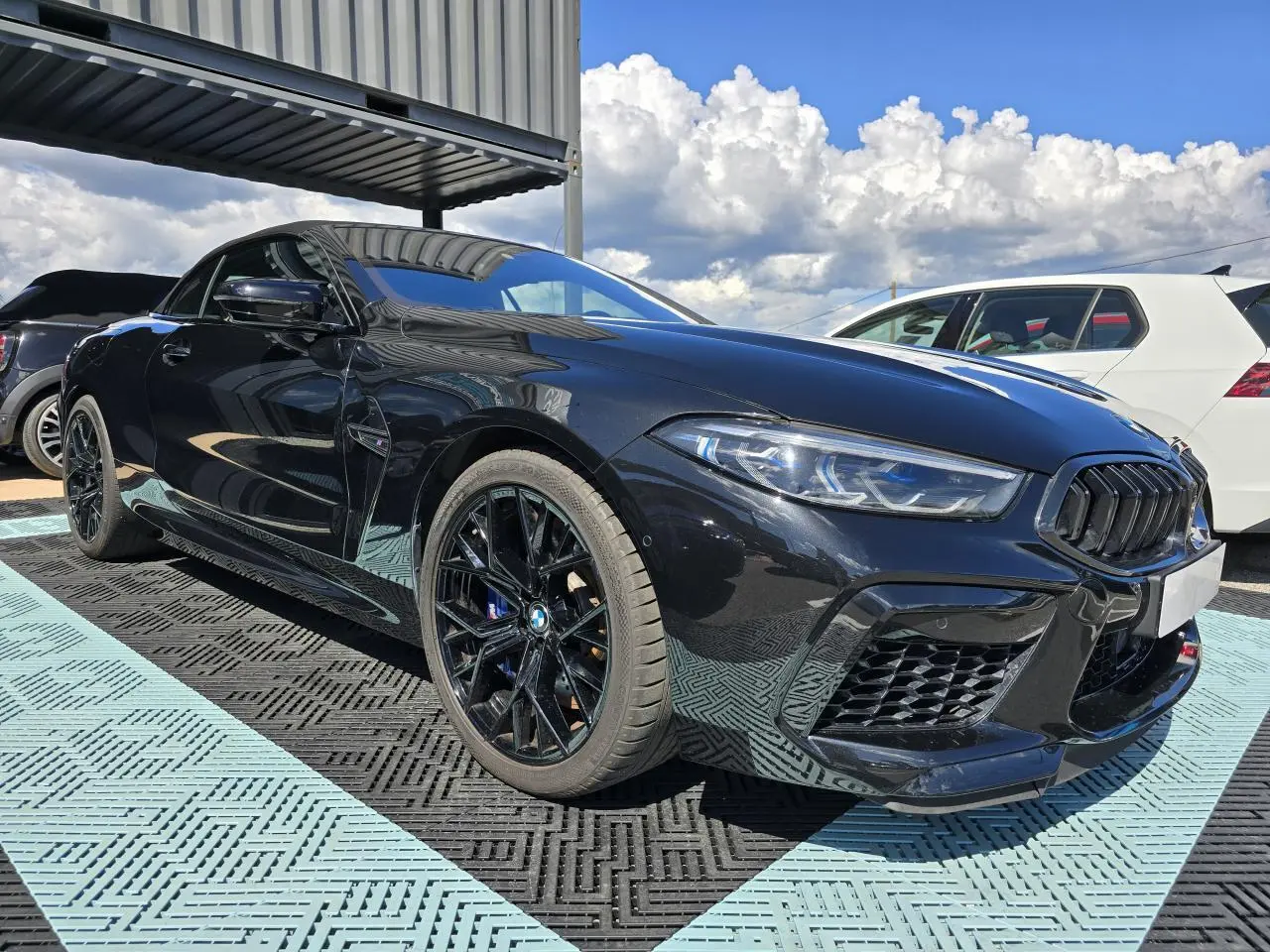 BMW Série 8 Cabriolet M8 Competition noir saphir métal, vue 3/4 avant côté gauche avec jantes noires brillantes.