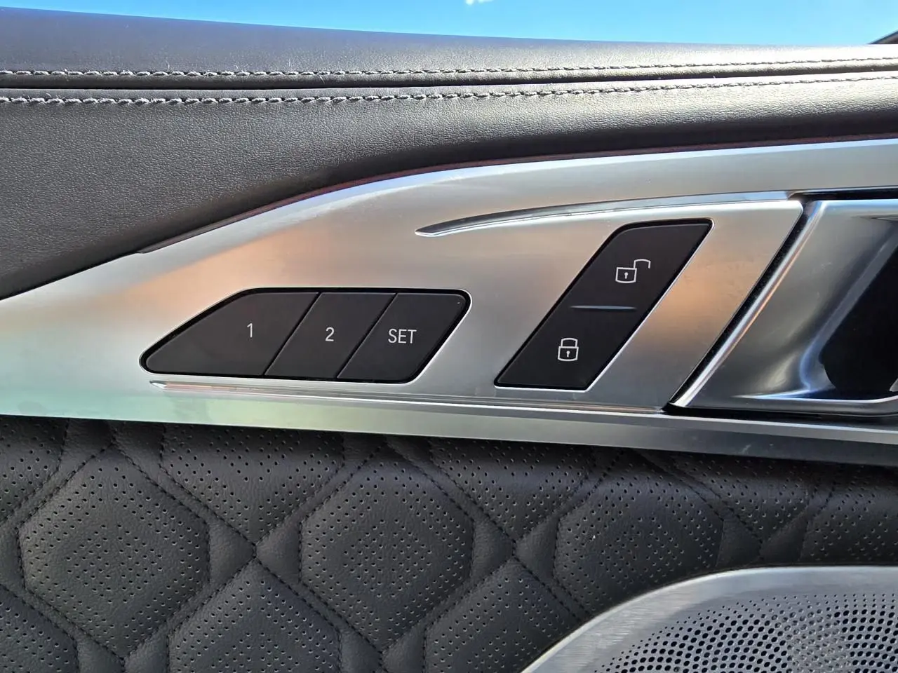 Détail des commandes de mémoire des sièges et verrouillage sur la portière côté gauche en cuir noir perforé d'une BMW Série 8 Cabriolet M8 Competition.