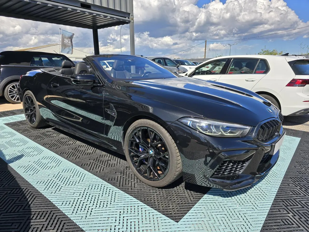 BMW Série 8 Cabriolet M8 Competition noir saphir métal, vue 3/4 avant droit avec jantes noires et capote ouverte.