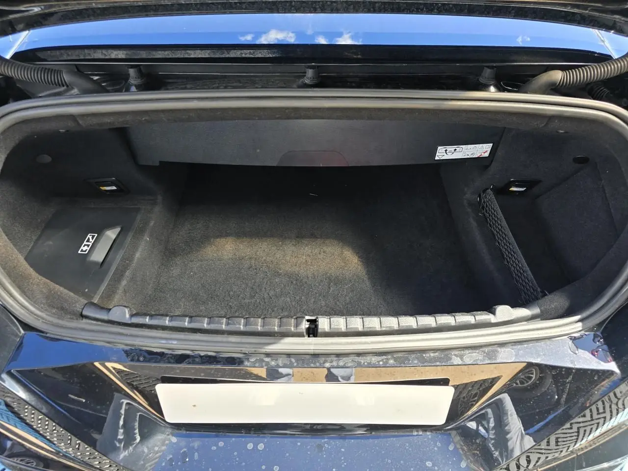 Coffre ouvert vu de dessus de la BMW Série 8 Cabriolet M8 Competition noir saphir métallisé, intérieur tissu noir.