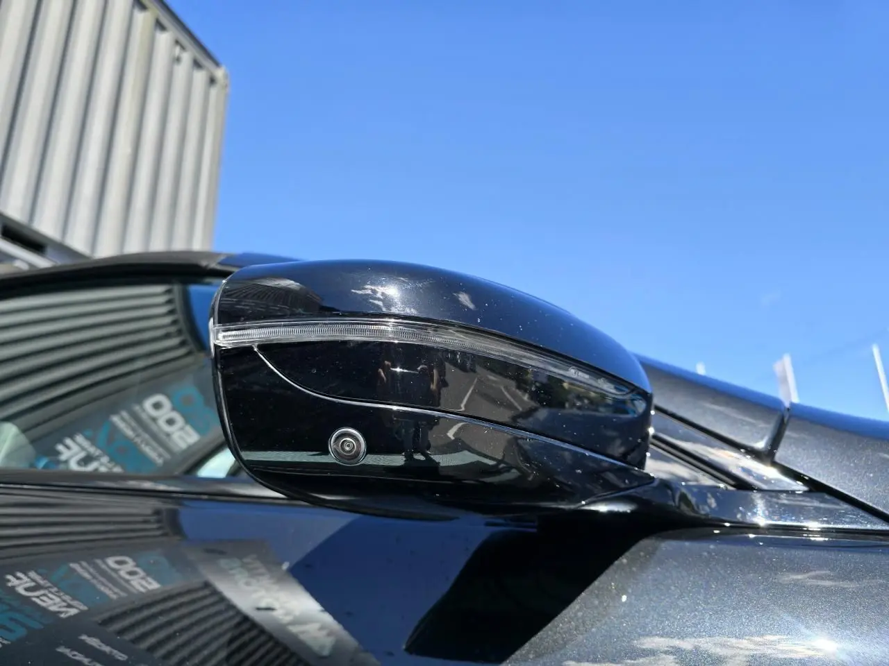Gros plan sur le rétroviseur droit noir brillant avec caméra intégrée d'une BMW Série 8 Cabriolet M8 Competition noir saphir métal.