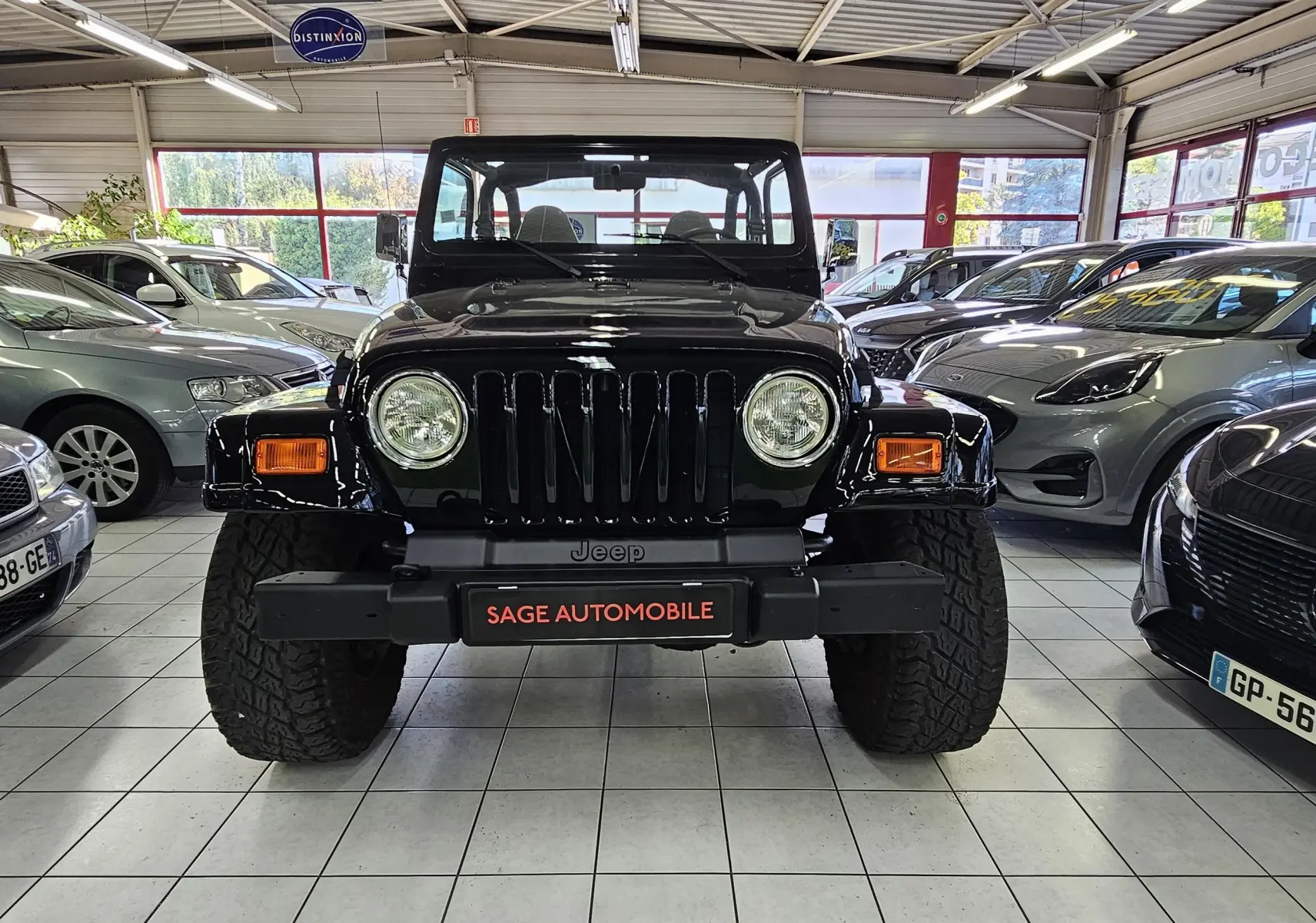 Vue avant du Jeep Wrangler noir de 2000 avec ses phares ronds et sa calandre à sept fentes, en intérieur showroom.