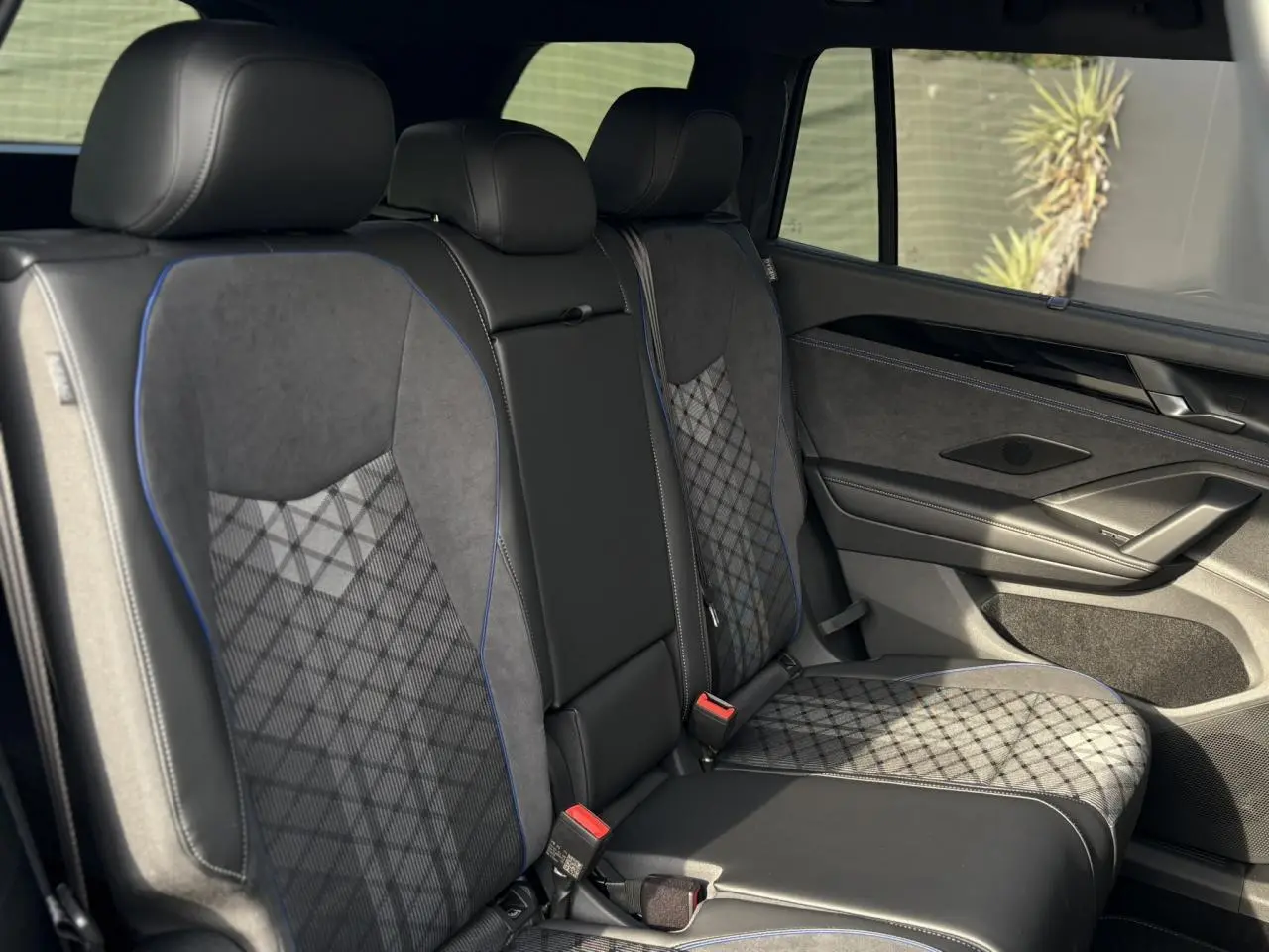 Vue intérieure côté droit des sièges arrière en tissu et cuir noir avec surpiqûres bleues du Volkswagen Tayron 2025.