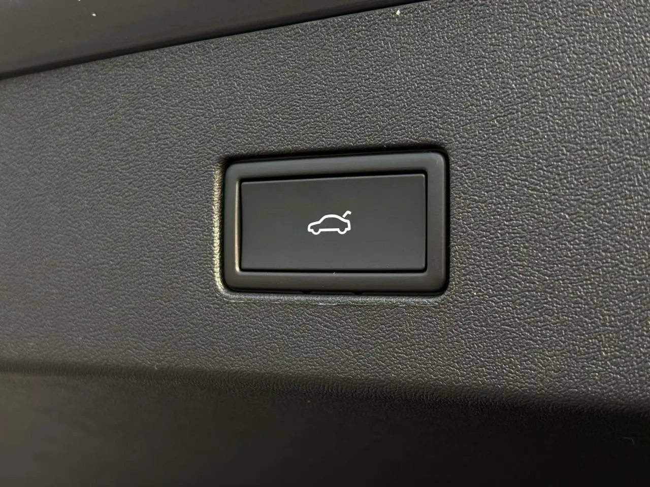 Bouton noir d'ouverture électrique du hayon sur Volkswagen Tayron gris dauphin, vue rapprochée intérieure.