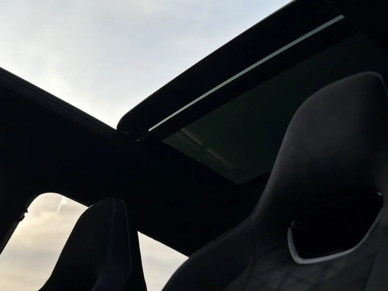 Toit ouvrant panoramique ouvert vu de l'intérieur sur siège avant sport noir du Volkswagen Tayron gris dauphin