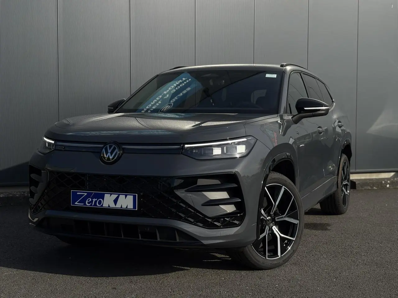 Volkswagen Tayron gris dauphin en 3/4 avant droit avec jantes alliage 20 pouces et calandre noire R-Line.