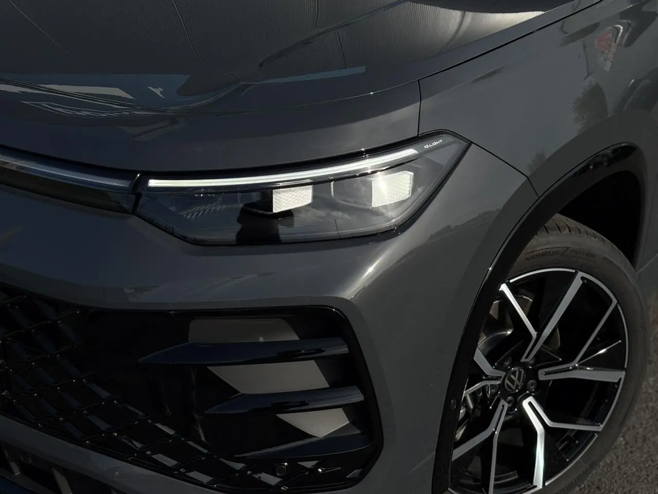 Gros plan sur l'avant droit gris dauphin du Volkswagen Tayron 2025, avec projecteur IQ.Light Matrix LED et jante alliage 20 pouces.