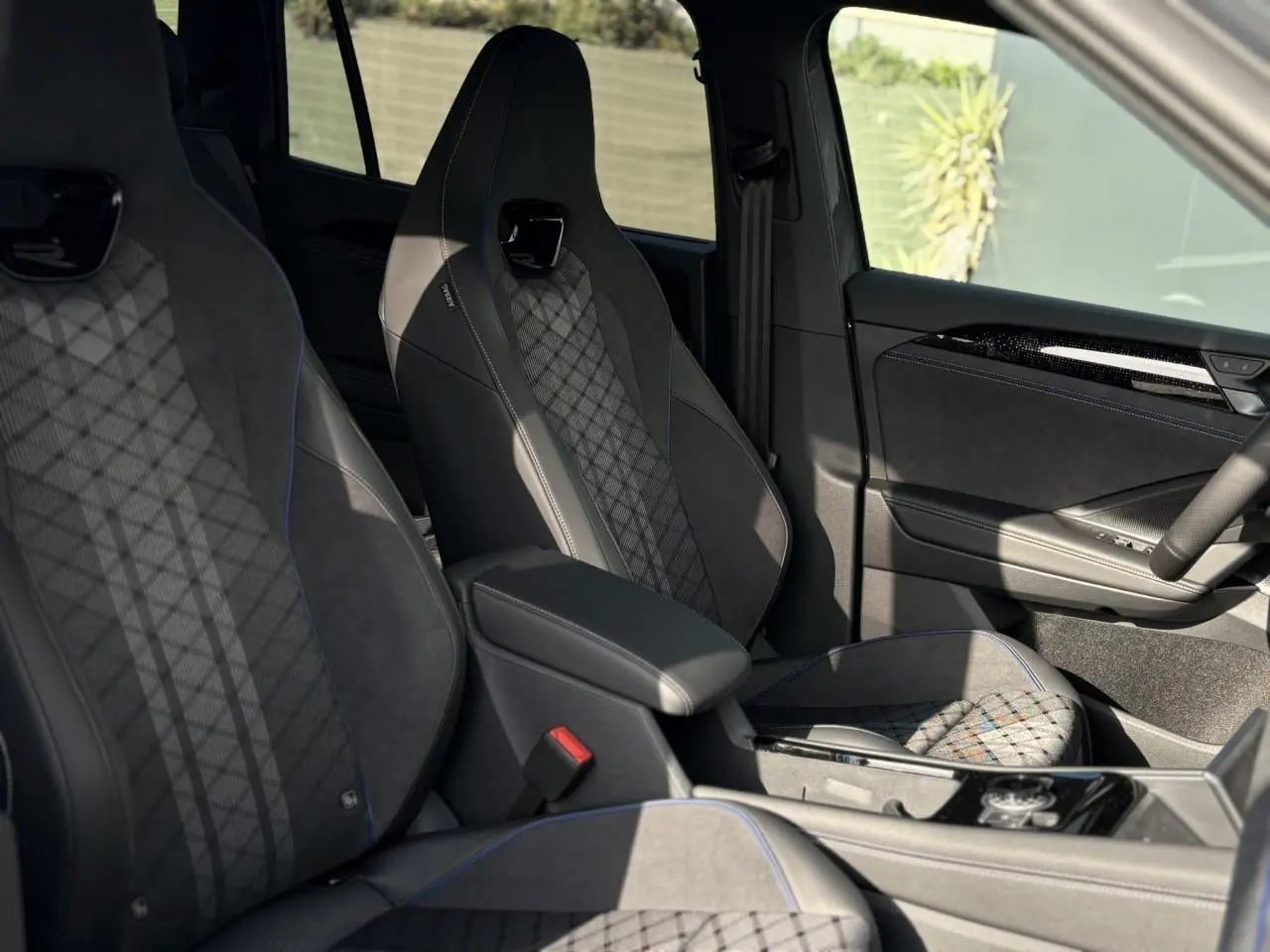 Vue intérieure côté droit du Volkswagen Tayron 2.0 TDI R-Line 7 places, sièges sport noirs avec surpiqûres bleues et détails en alcantara.