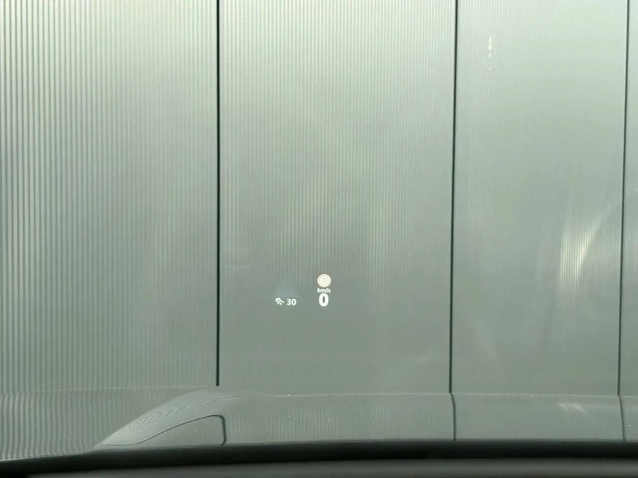 Vue depuis l'intérieur du Volkswagen Tayron gris dauphin, affichage tête haute projetant la vitesse et limite sur pare-brise.