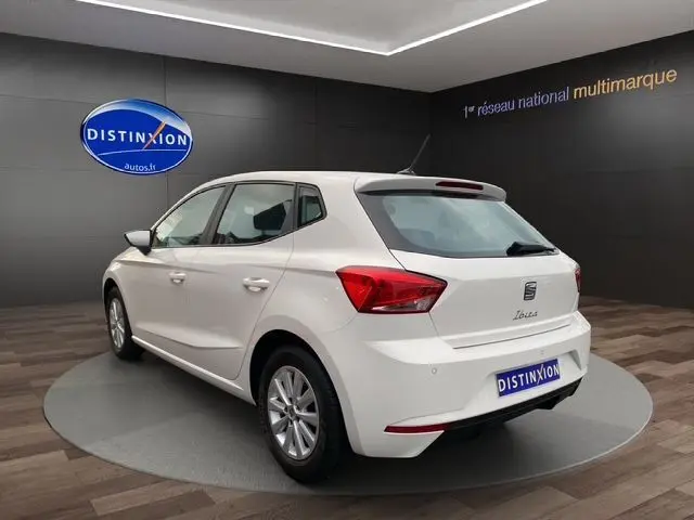 Vue 3/4 arrière d'une SEAT Ibiza blanche Candy 2023, compacte cinq portes avec feux arrière anguleux et jantes alliage.