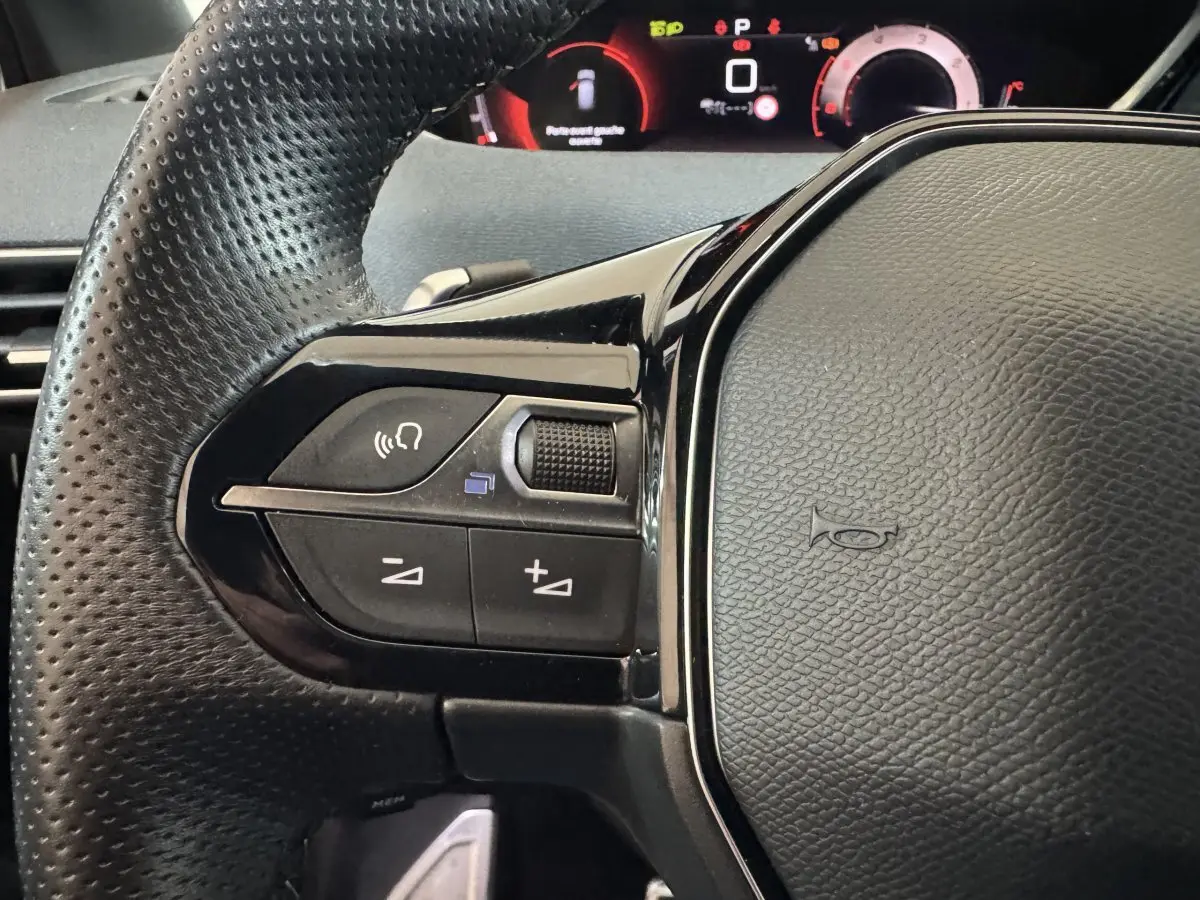 Gros plan sur le volant cuir perforé côté gauche du Peugeot 3008 GT 2021 avec commandes vocales et tableau de bord numérique.