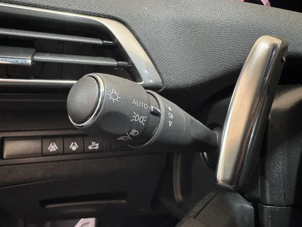 Gros plan sur la commande des phares et clignotants à gauche du volant dans l'habitacle gris du Peugeot 3008 GT 2021.