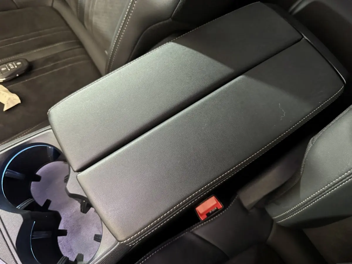 Vue rapprochée de l'accoudoir central noir et des sièges en cuir gris foncé à coutures blanches du Peugeot 3008 GT 2021.