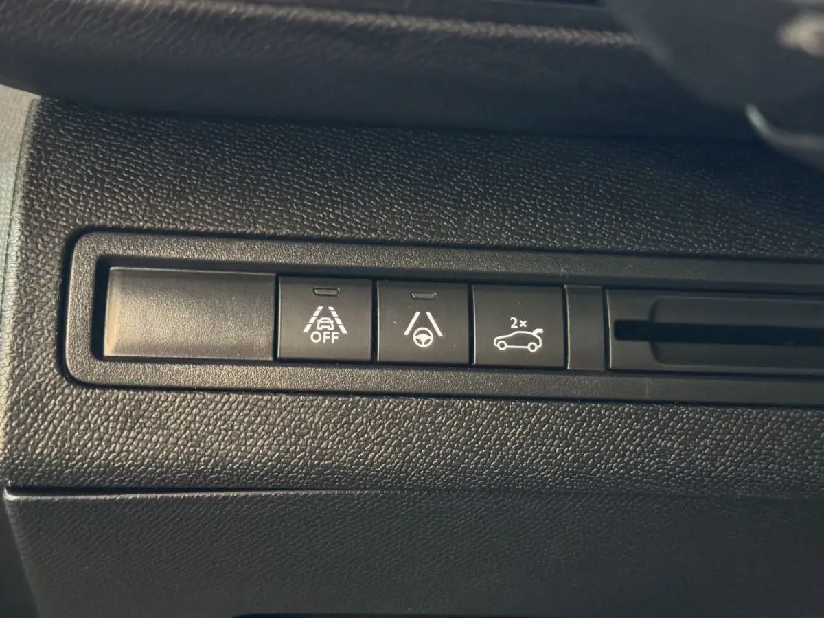 Gros plan sur les boutons de commande d'aide à la conduite dans un Peugeot 3008 gris clair, version GT 2021.