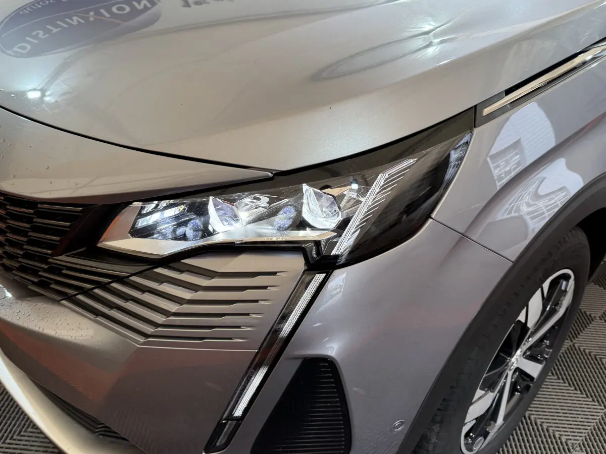 Gros plan sur le phare avant droit du Peugeot 3008 gris clair 2021 avec détails LED et calandre moderne.