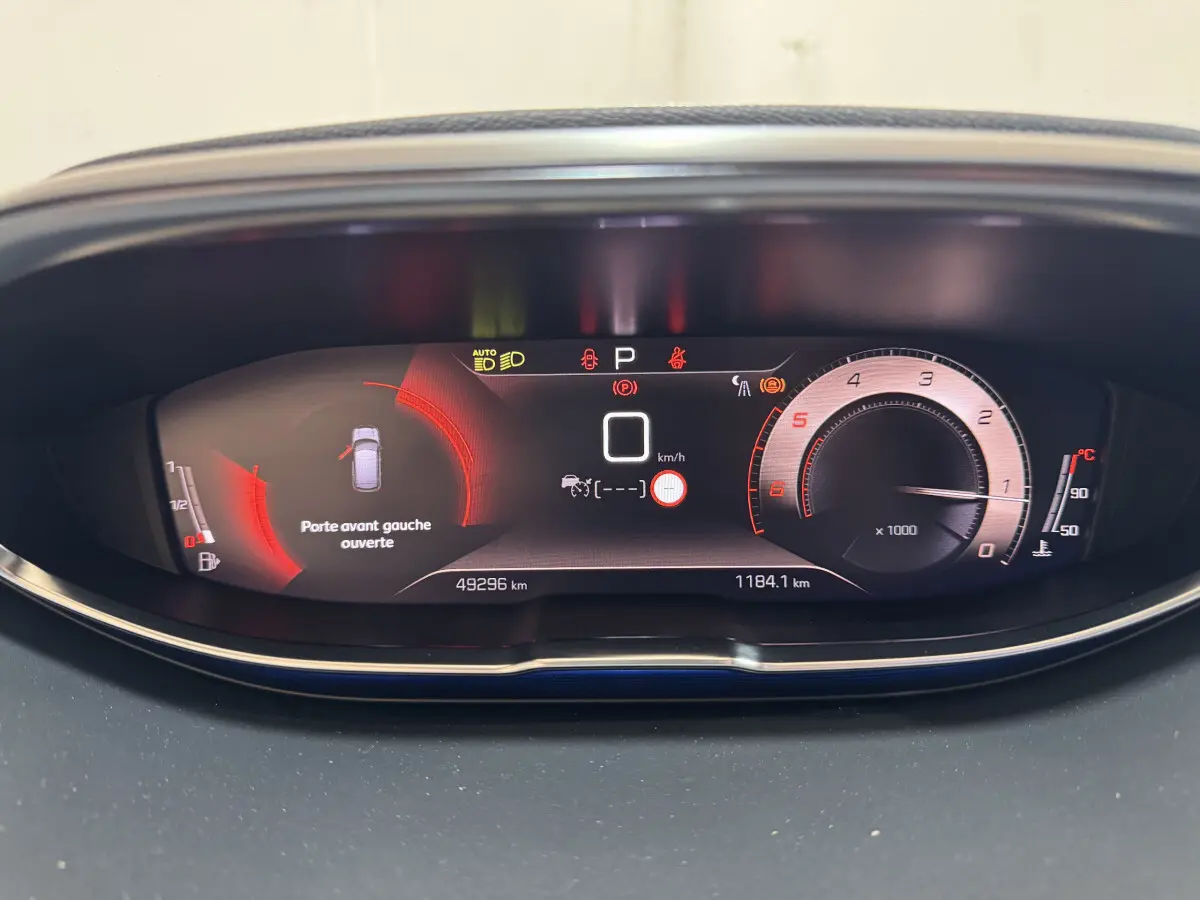 Tableau de bord numérique du Peugeot 3008 GT 2021 avec affichage de vitesse, compte-tours et alerte porte avant gauche ouverte.