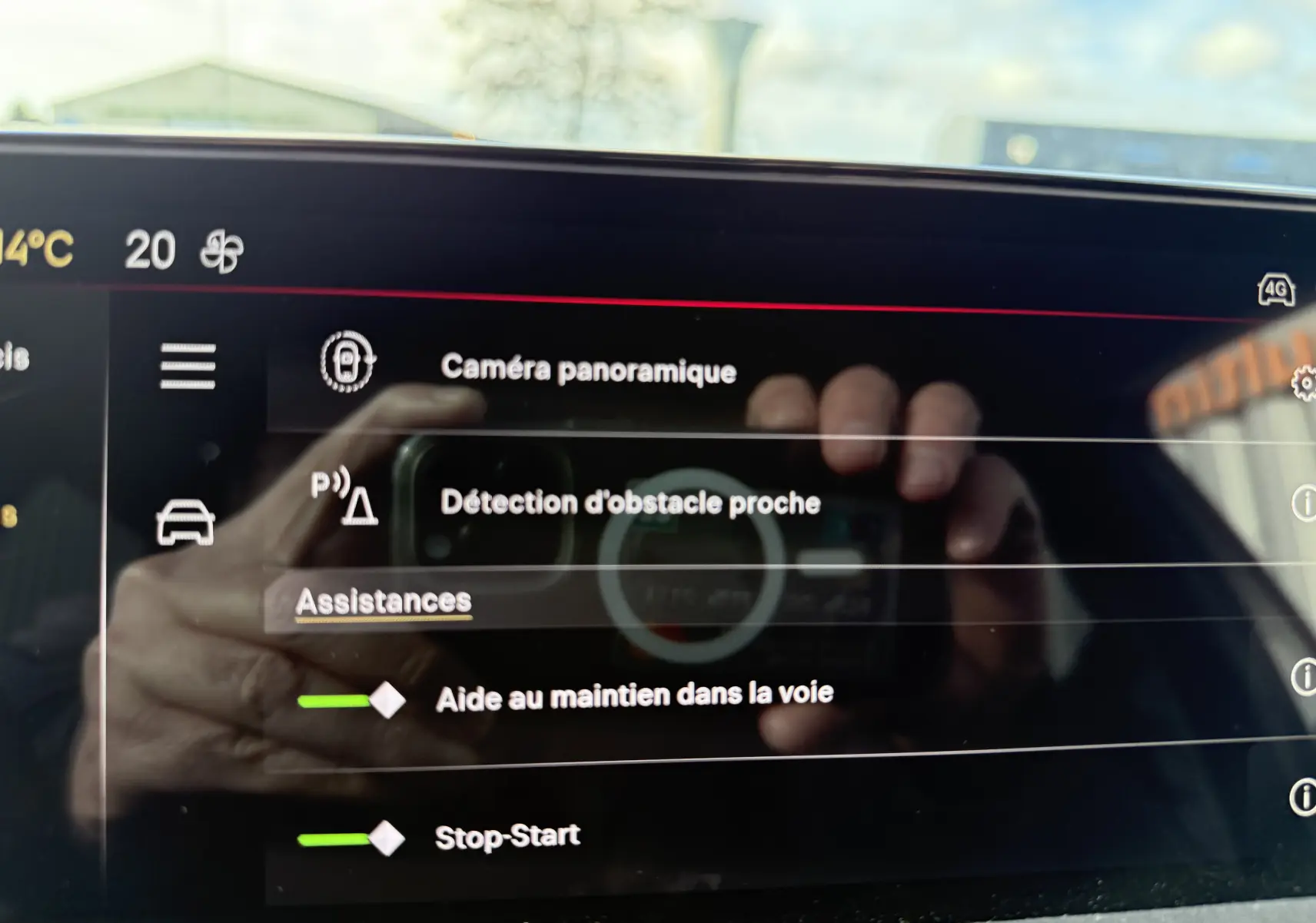Écran tactile intérieur de la DS3 hybride 2025 affichant les assistances à la conduite avec reflet de mains.