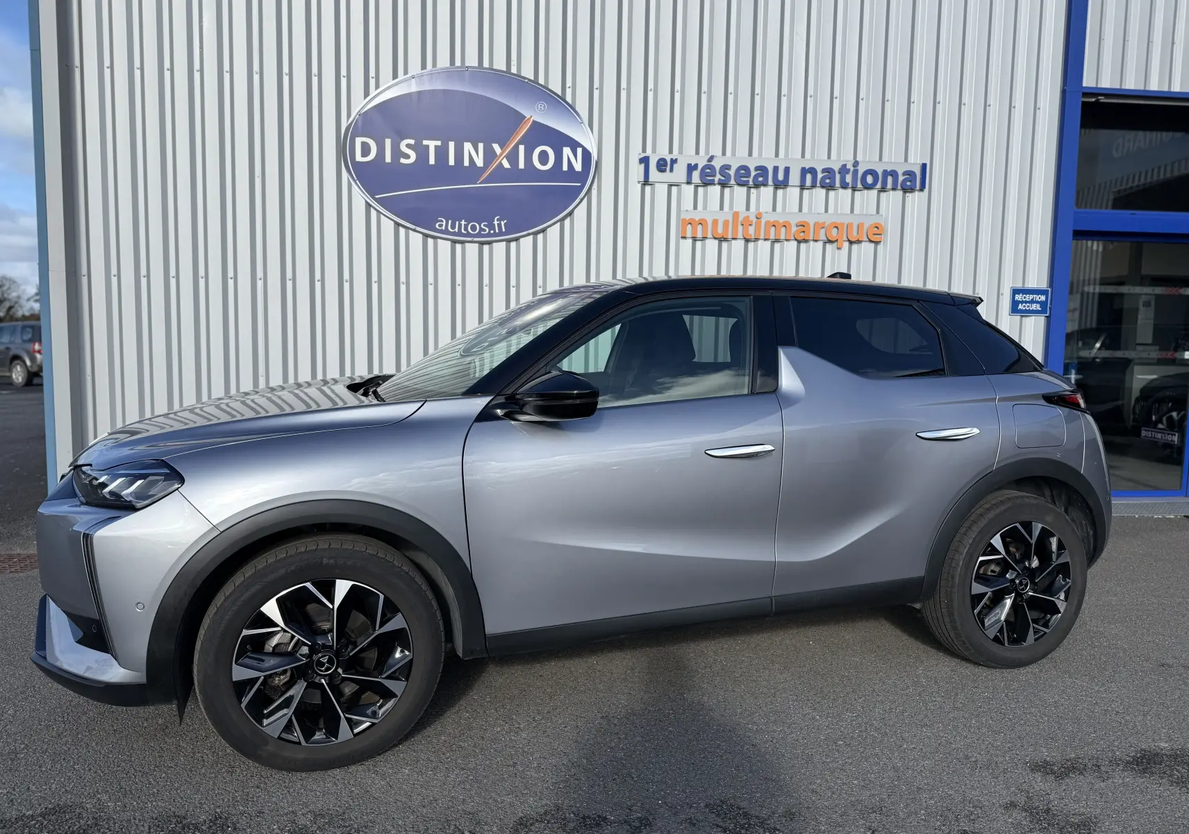 Vue de profil côté gauche d'une DS3 hybride 2025 gris Artense avec toit noir et jantes noires bicolores.