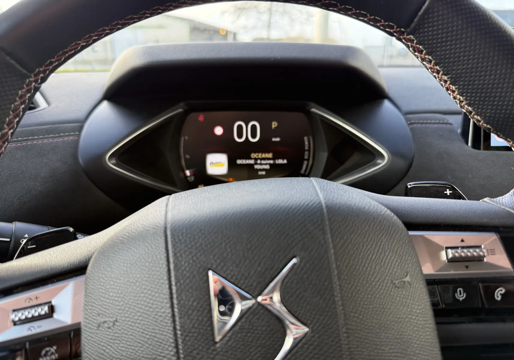 Vue rapprochée du volant en cuir noir avec logo DS et tableau de bord numérique affichant la vitesse à 0 km/h.