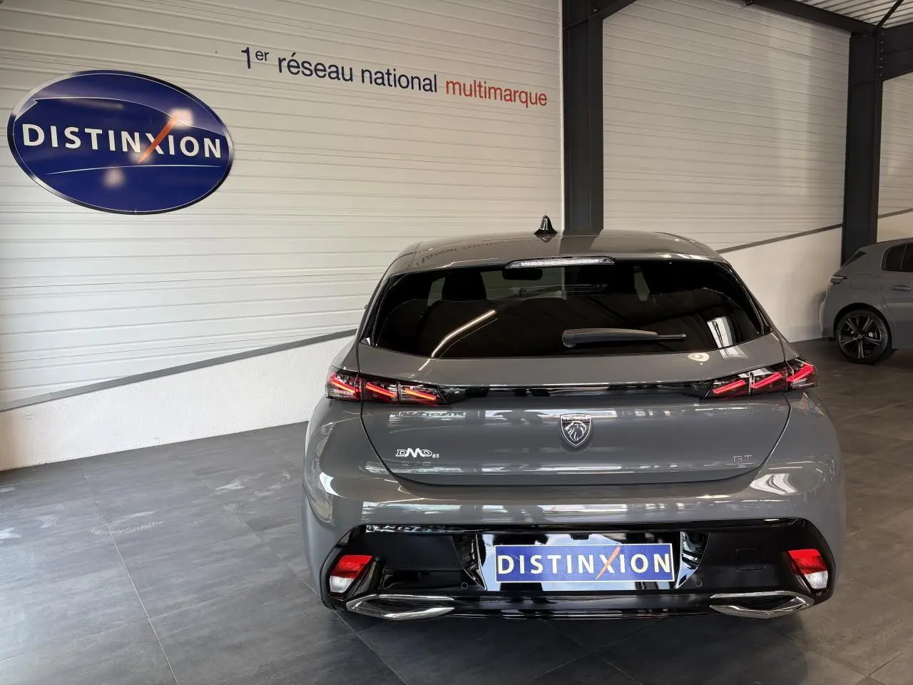 Vue arrière d'une Peugeot 308 GT 2025 gris selenium avec feux arrière à signature lumineuse griffe à griffe.
