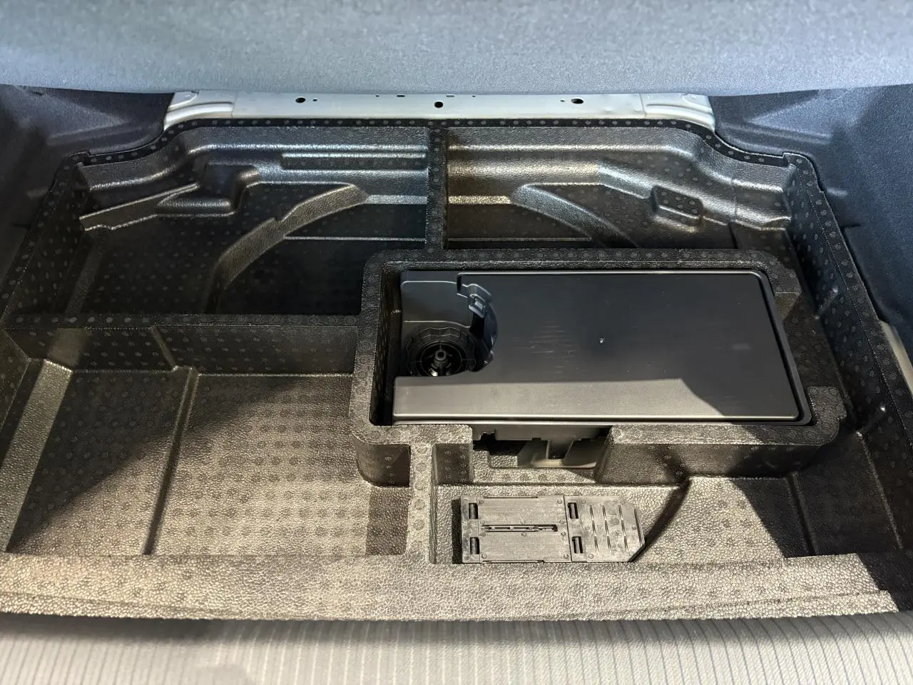 Rangement sous le coffre de la Peugeot 308 2025, compartiment en mousse noire avec kit de dépannage pneumatique.