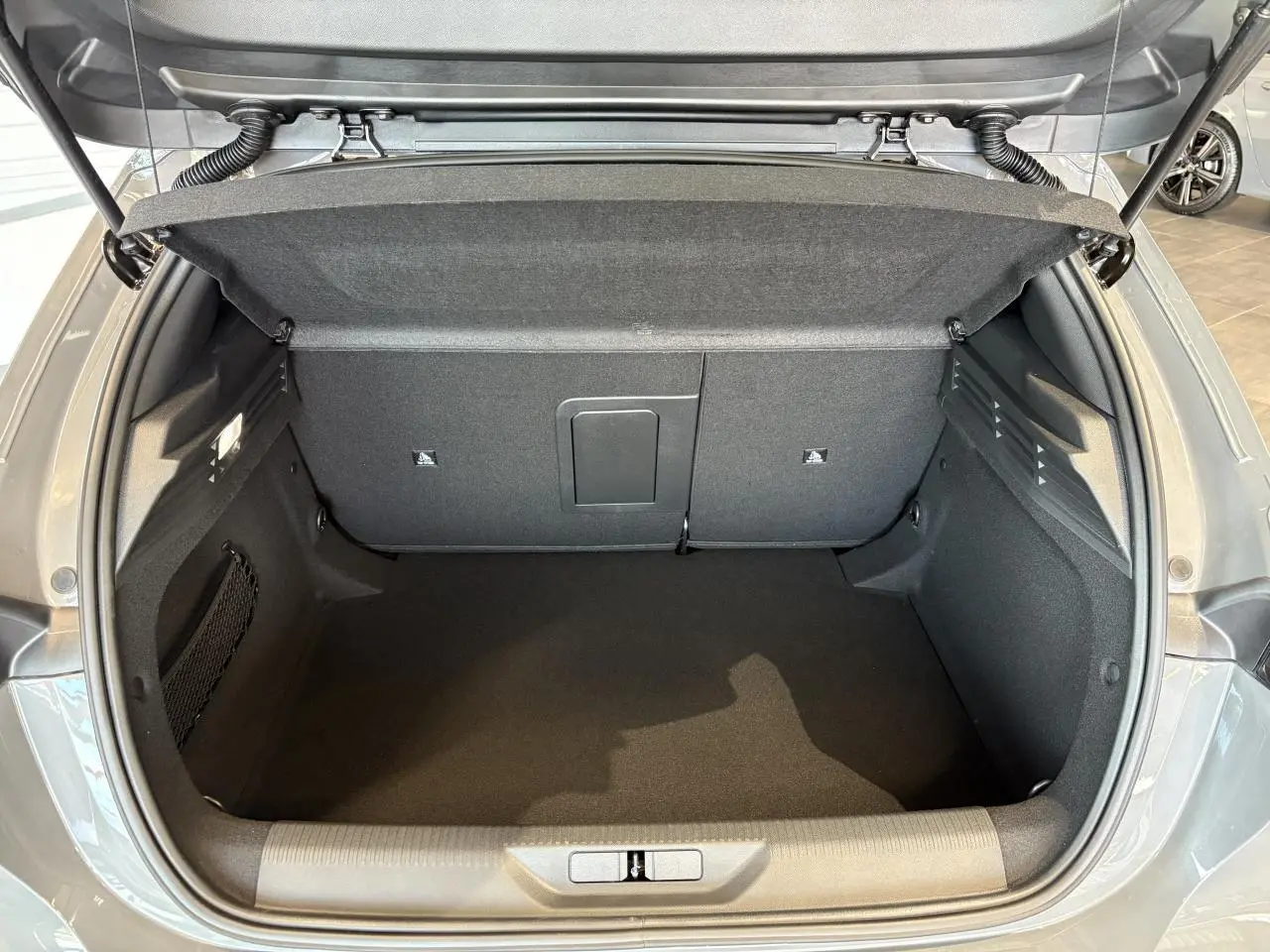 Coffre ouvert vu de l'arrière d'une Peugeot 308 gris selenium, intérieur spacieux et bien fini.