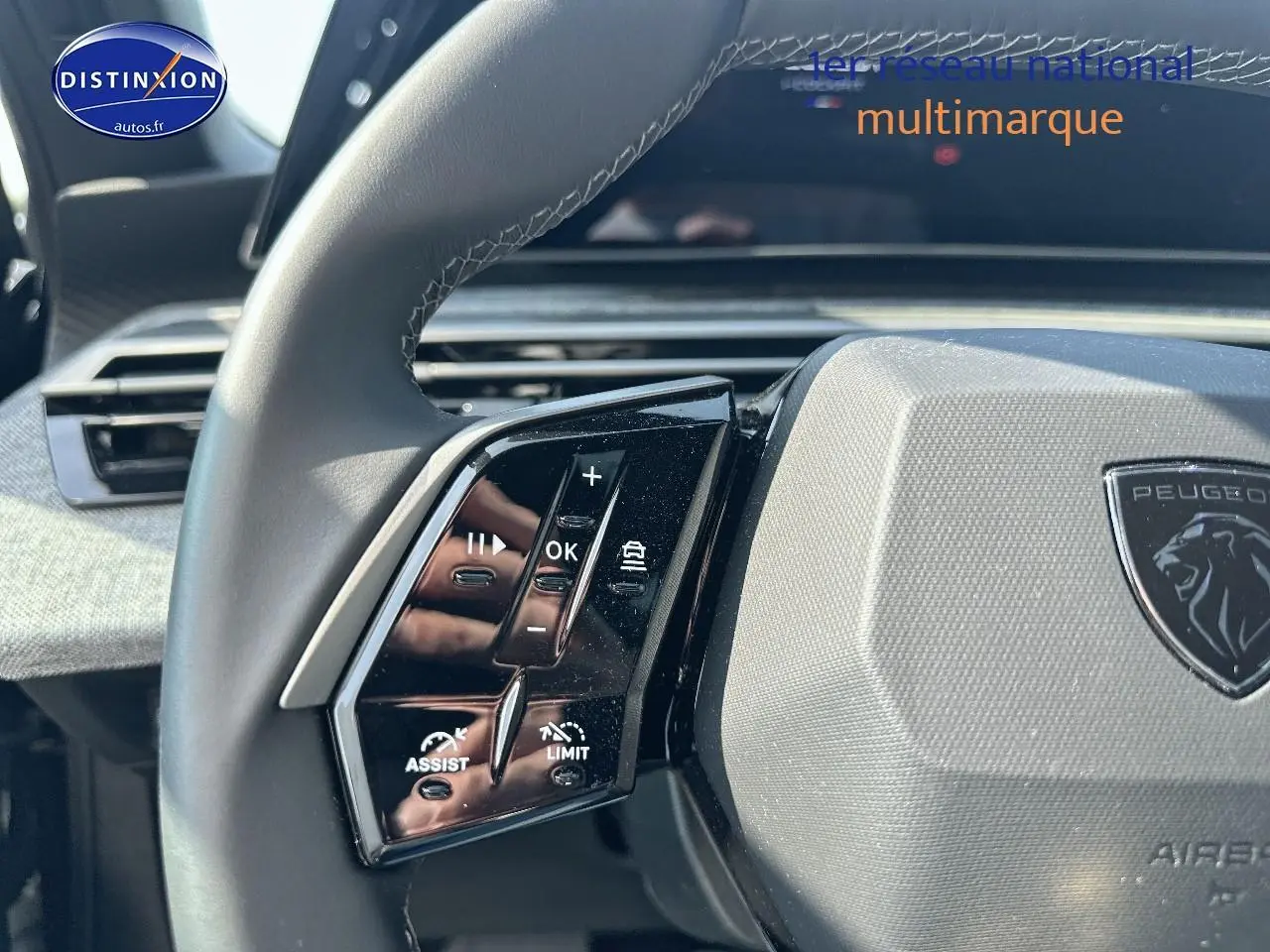 Gros plan sur le volant cuir noir du Peugeot 3008 2025, avec commandes multifonctions et logo lion central gris.