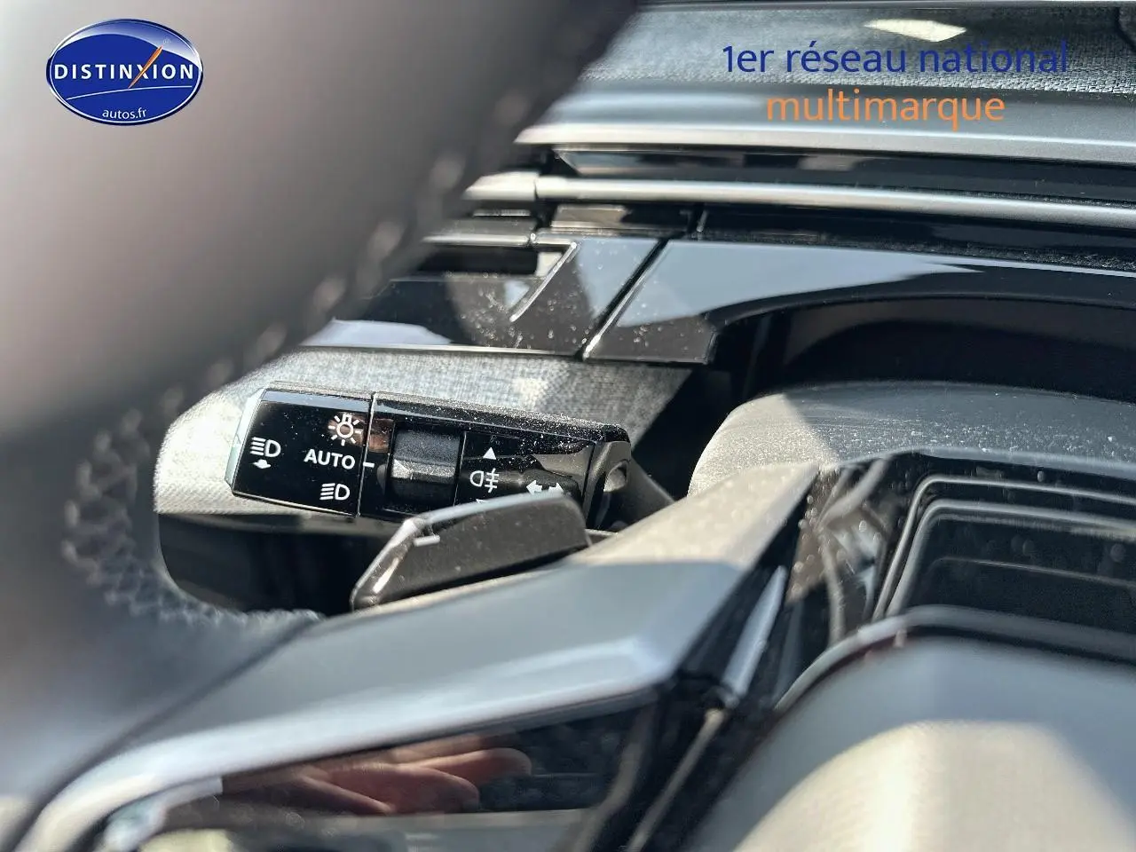 Détail du commodo d'éclairage sur le côté gauche du volant d'un Peugeot 3008 noir perla nera 2025.