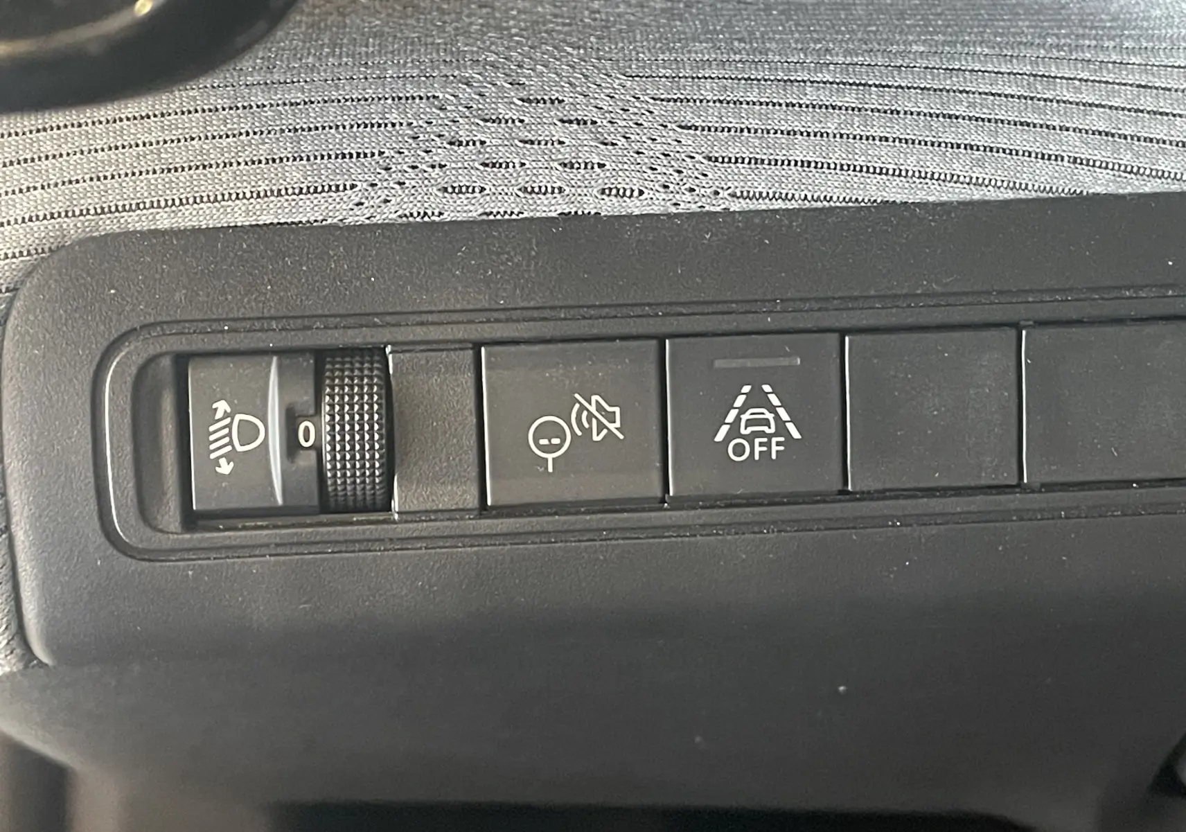 Gros plan sur les commandes du tableau de bord de la Citroën E-C3 113 MAX noire, avec réglage des phares et aides à la conduite.
