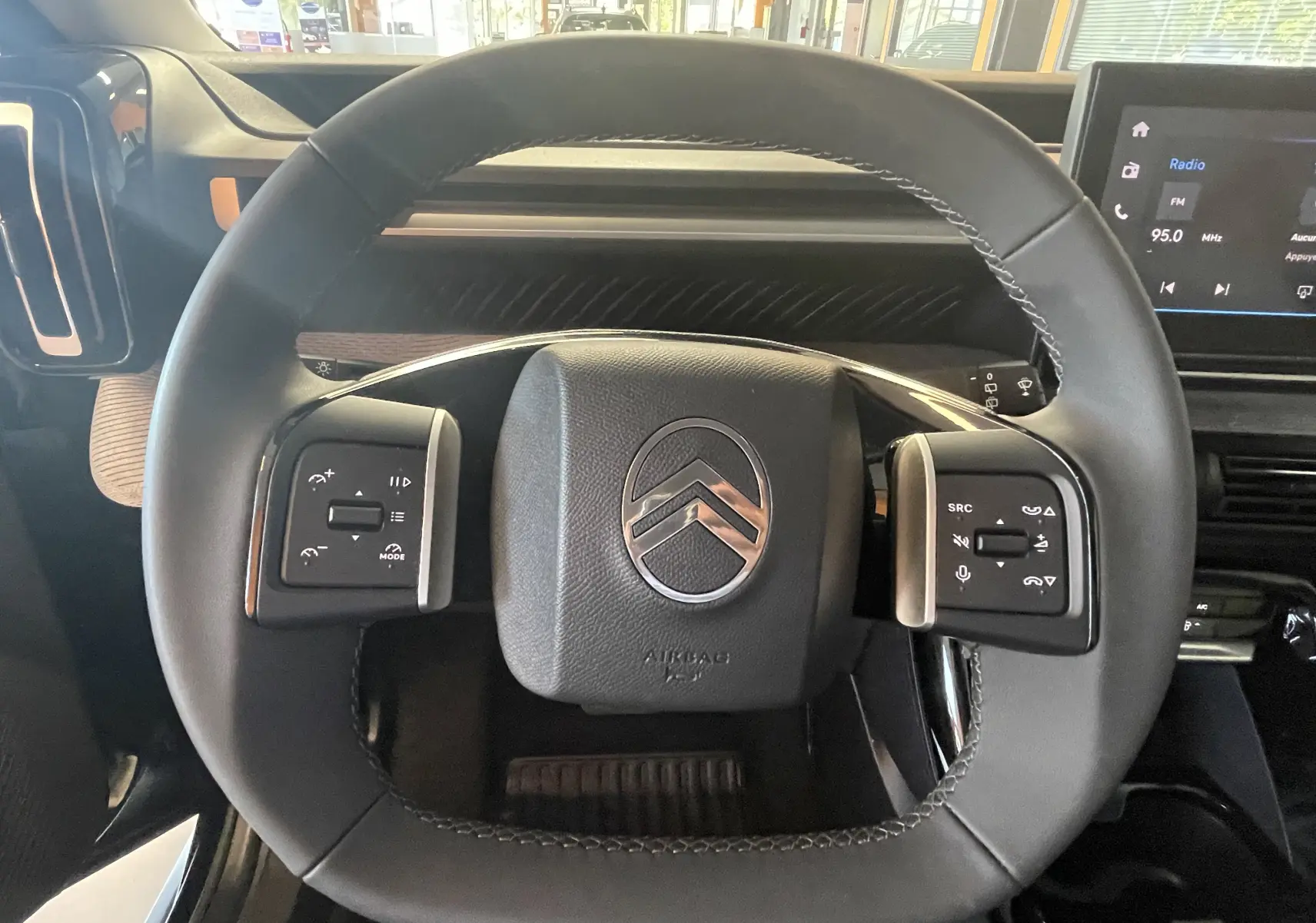 Vue rapprochée du volant noir de la Citroën E-C3 113 MAX 2025 avec commandes intégrées et logo central chromé.