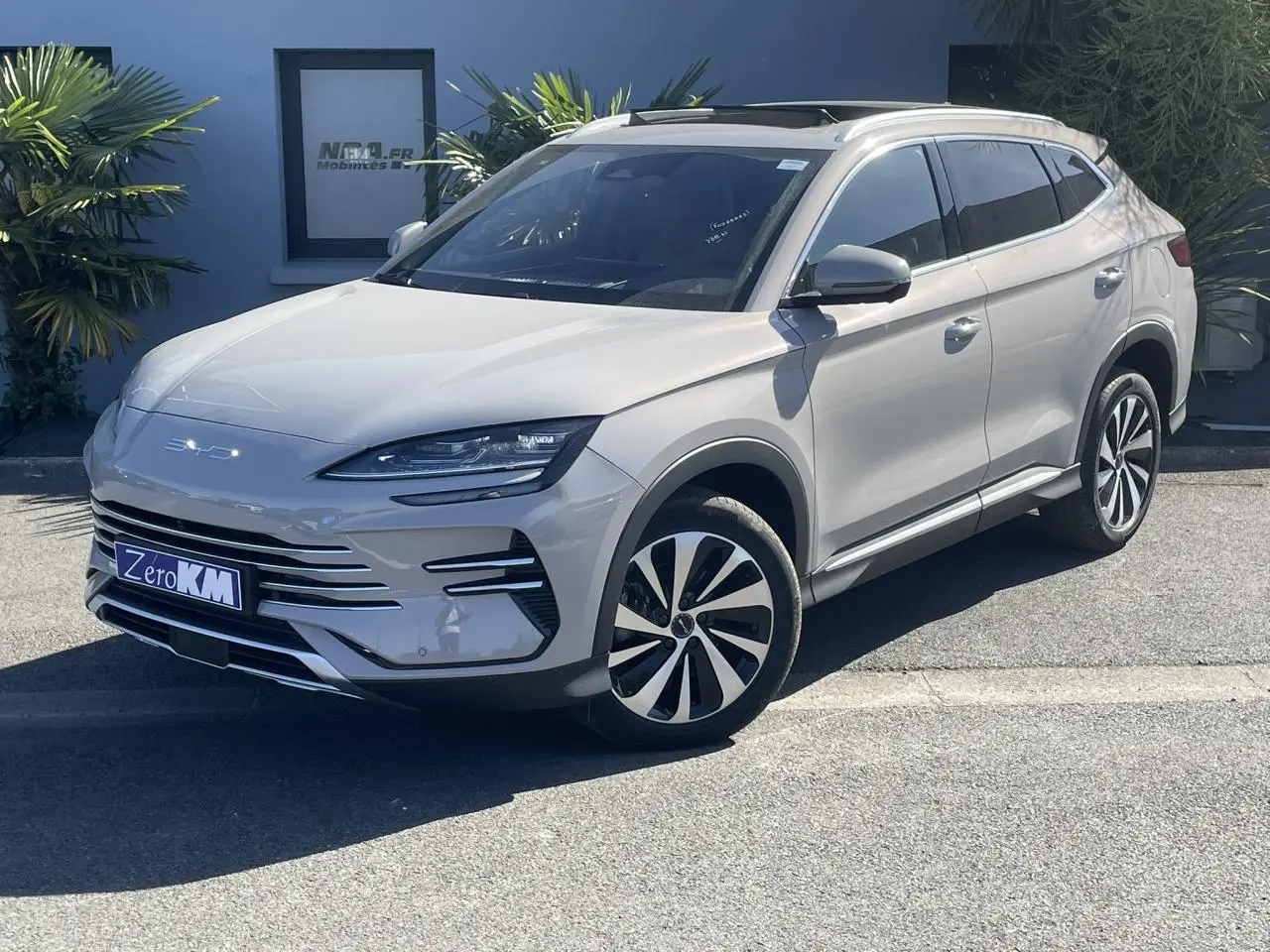 Vue 3/4 avant droite du SUV BYD SEAL U 2025 en beige métallisé Boundless Cloud avec jantes bicolores et barres de toit.