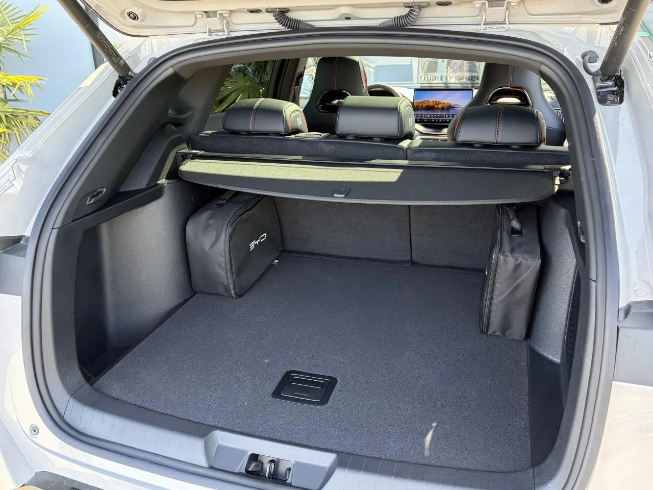 Coffre ouvert du BYD SEAL U beige Boundless Cloud, montrant un espace de chargement avec cache-bagages et sacs latéraux.