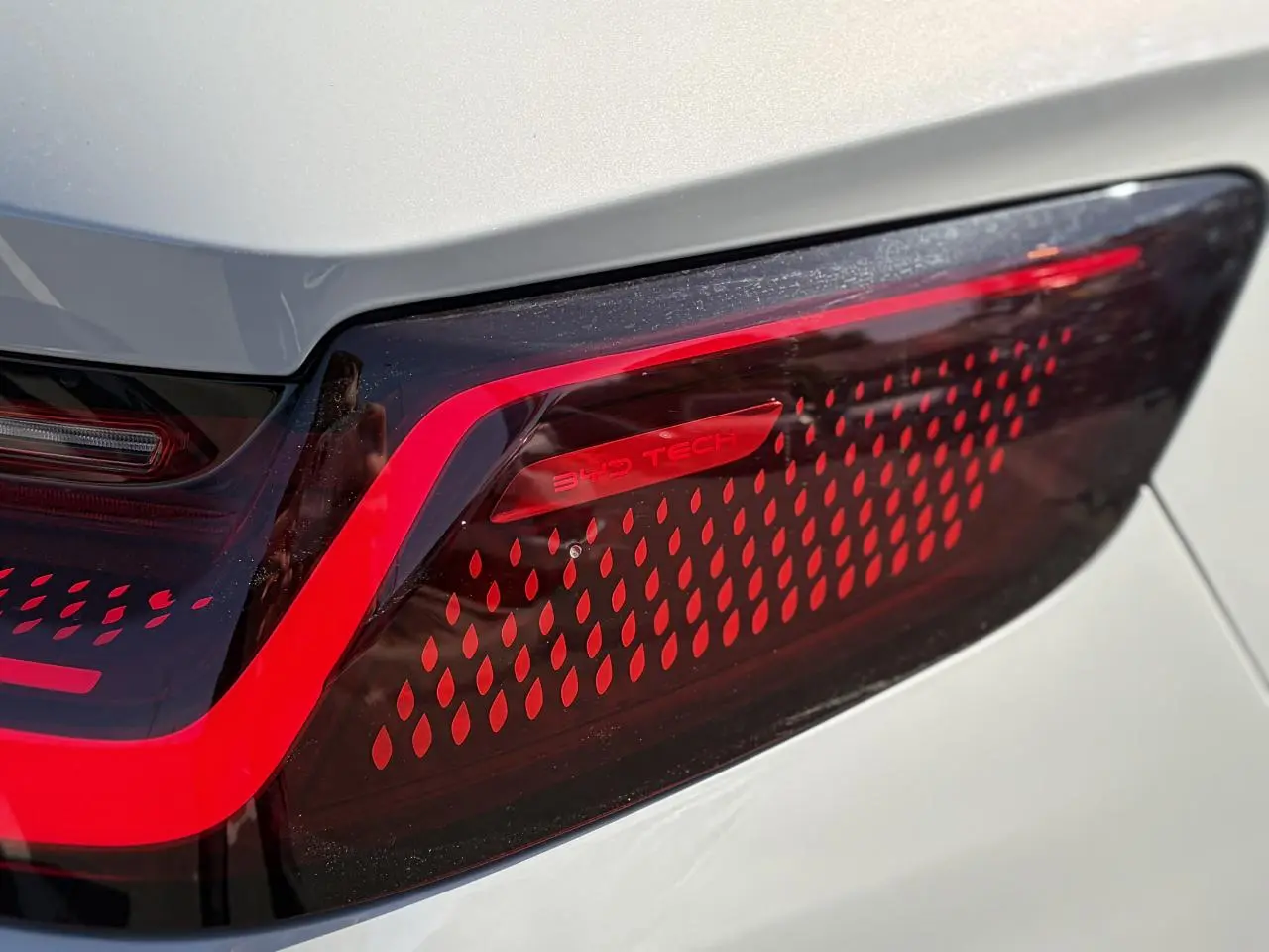 Gros plan sur le feu arrière droit rouge du BYD SEAL U 2025 en peinture métallisée Boundless Cloud beige.