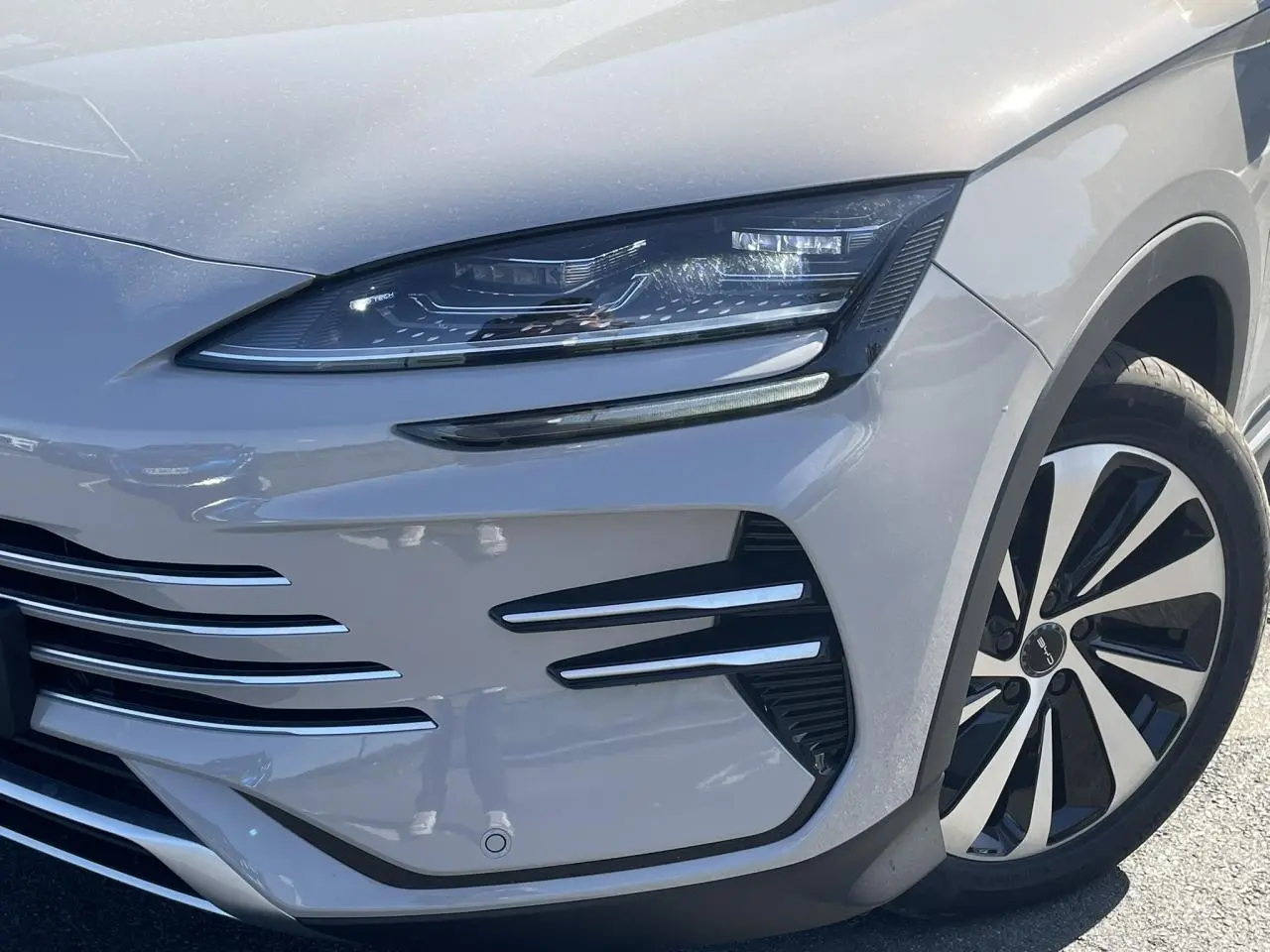 Gros plan sur l'avant droit du BYD SEAL U 2025 en peinture métallisée Boundless Cloud beige avec phares LED et jante bicolore.